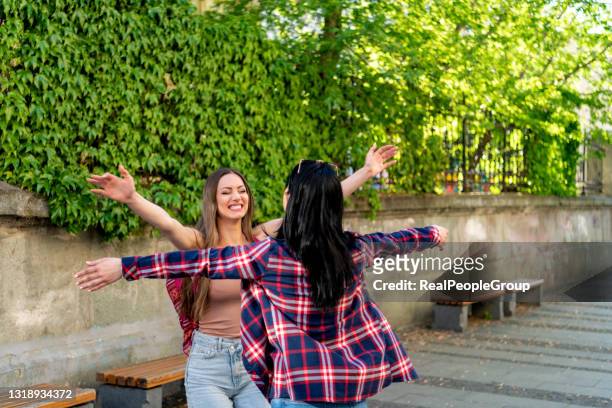 happy meeting of two friends hugging in the street - apologize imagens e fotografias de stock