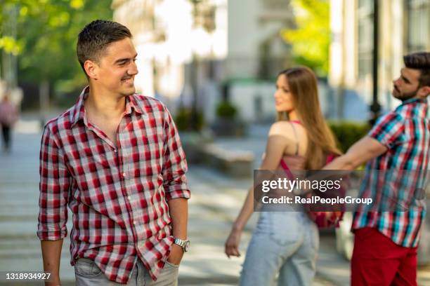 disloyal young  woman looking another man and her angry boyfriend looking at her on the street - girlfriend meme stock pictures, royalty-free photos & images