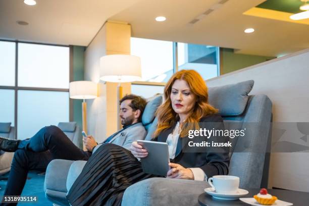 coworkers using technologies at airport lounge - business class lounge stock pictures, royalty-free photos & images