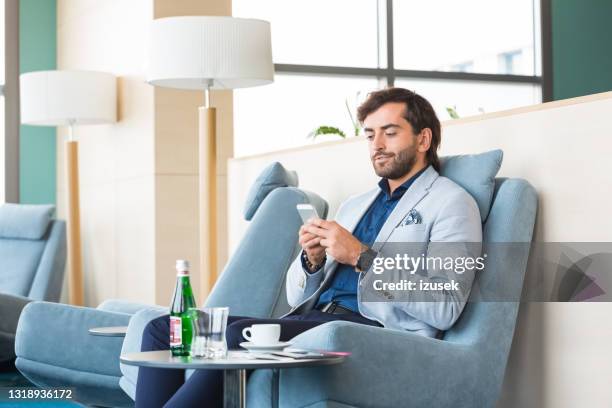 businessman using smart phone at airport - airport vip lounge stock pictures, royalty-free photos & images
