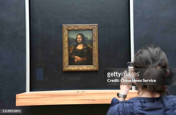 Visitor takes photos of the painting 'Mona Lisa' at the Louvre Museum on its reopening day on May 19, 2021 in Paris, France. Louvre Museum reopened...