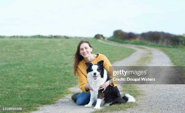 woman sitting with dog on country lane. - single lane road stock-fotos und bilder