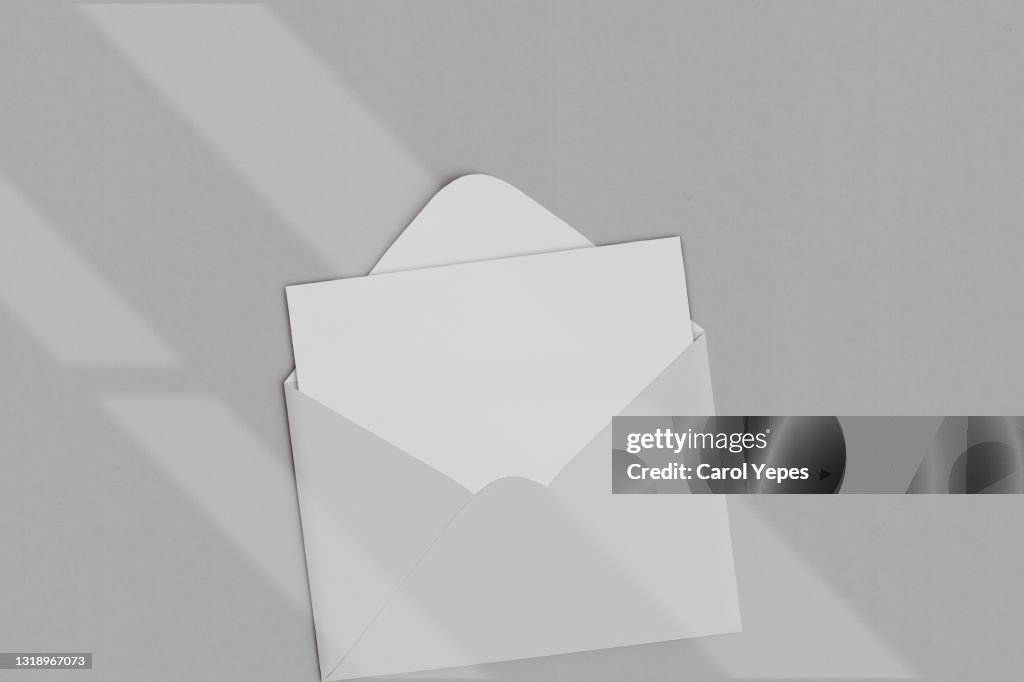 Opened brown envelope with blank card on grey background with shadows