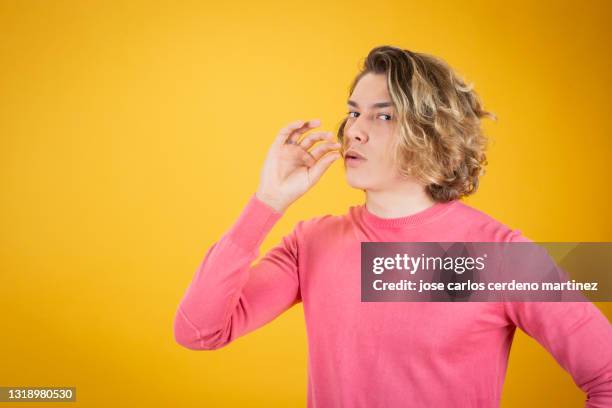 handsome young man looking at camera while making smoking gesture with his hands - quit smoking stock-fotos und bilder