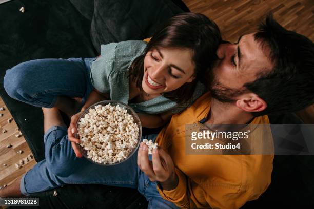 vista superior de un hombre besando a su mujer mientras ve la televisión - lovers 2020 film fotografías e imágenes de stock