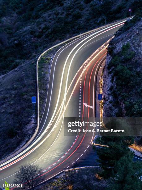 high angle view of light trails on road with an s-shaped curve at night. - arrows landscapes stock pictures, royalty-free photos & images