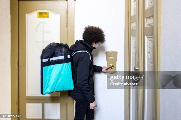 lebensmittellieferant drückt türklingel einer wohnung - doorbell stock-fotos und bilder