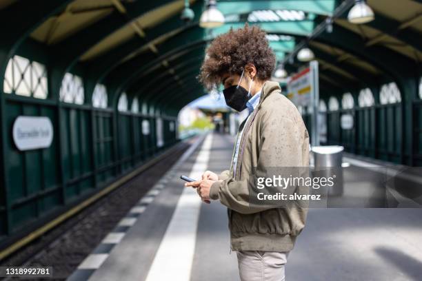 mann mit gesichtsmaske wartet auf zug an stadt-u-bahn-station - ubahn station stock-fotos und bilder