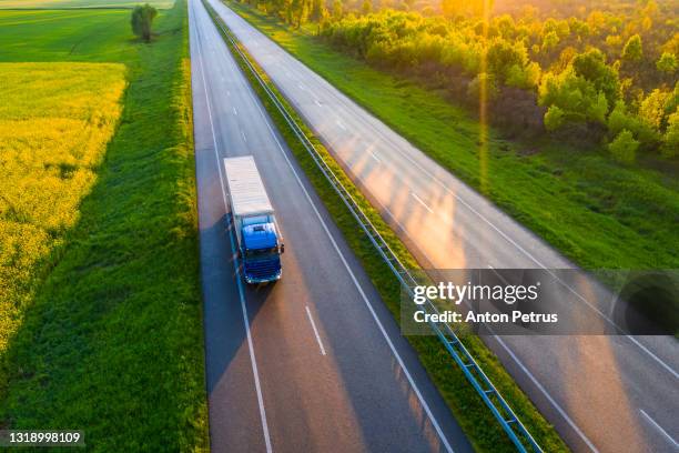 aerial view of truck driving on asphalt road along the green fields in rural landscape. - landwirtschaftsgeräte ansicht von oben stock-fotos und bilder