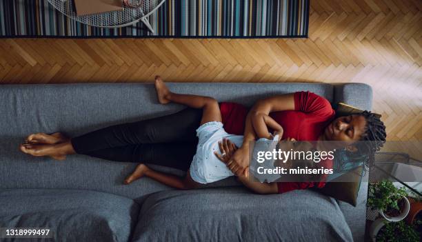 top view of beautiful mother with little daughter sleeping on sofa - mom resting stock pictures, royalty-free photos & images