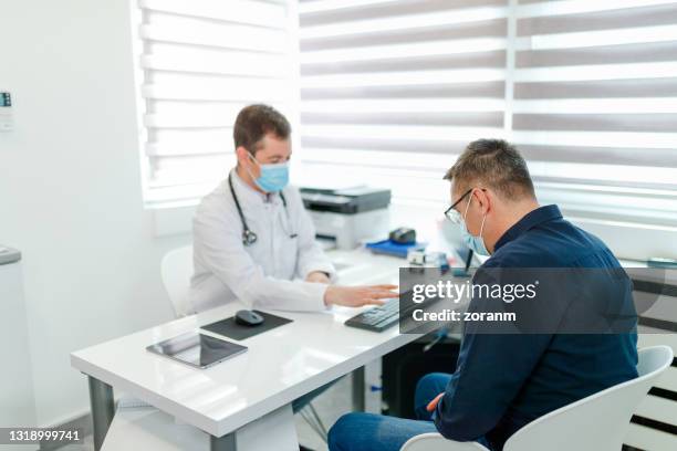 patient sitting at doctor's office and waiting for referral, wearing protective face masks - referral stock pictures, royalty-free photos & images