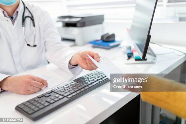 passing prescription to female patient over the desk in doctor's office - referral stock pictures, royalty-free photos & images