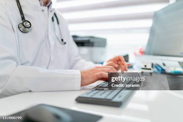 digitando no teclado do computador, médico usando tecnologia moderna no trabalho - registo-médico-eletrónico - fotografias e filmes do acervo