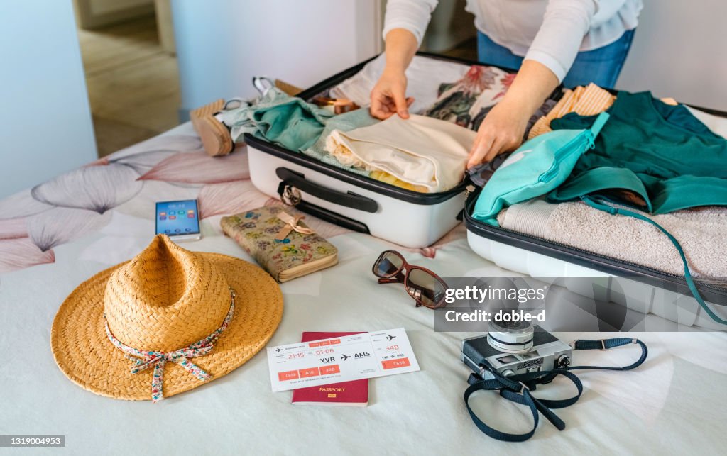 Unrecognizable woman preparing suitcase for summer holidays