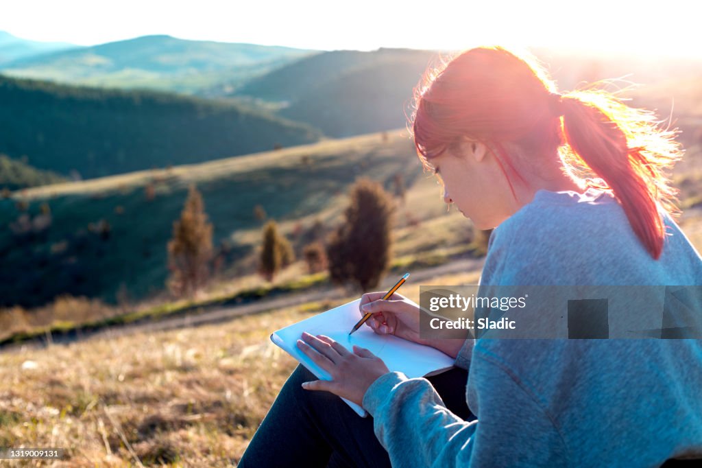 A young woman enjoying the sunset from the mountain top