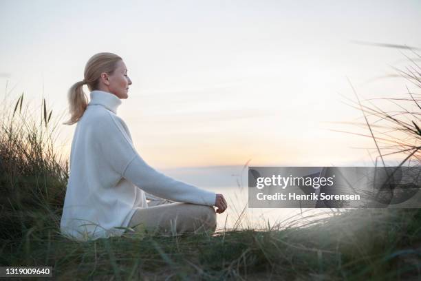 woman in sunset - meditation sitting foto e immagini stock