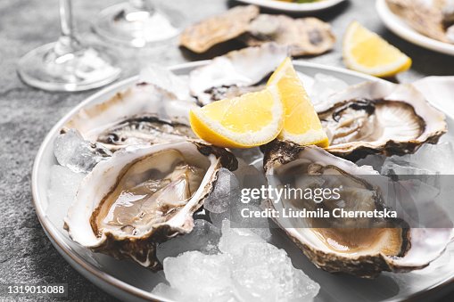 Ostriche fresche con limone e ghiaccio su tavola grigia, primo piano Ostriche fresche con limone e ghiaccio su tavola grigia, primo piano
