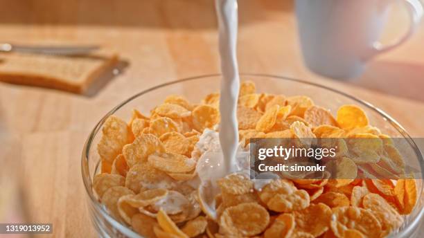 leche vertiendo en un tazón de copos de maíz - corn flakes fotografías e imágenes de stock