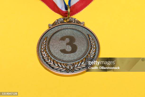 bronze medal of sporting achievement for the third classified, on a yellow background. - golden medals of merit in work ceremony stock pictures, royalty-free photos & images
