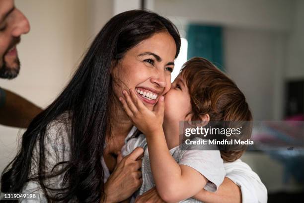 boy kissing his mother on the cheek while sitting together at home - week three stock pictures, royalty-free photos & images