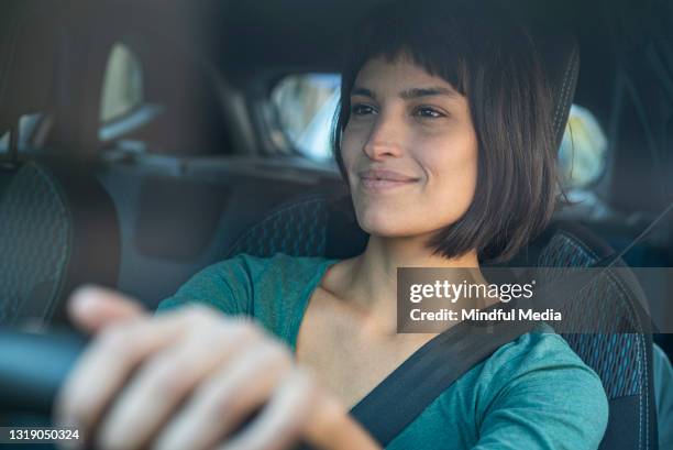 contented woman looking through windshiled while driving - new car stock pictures, royalty-free photos & images