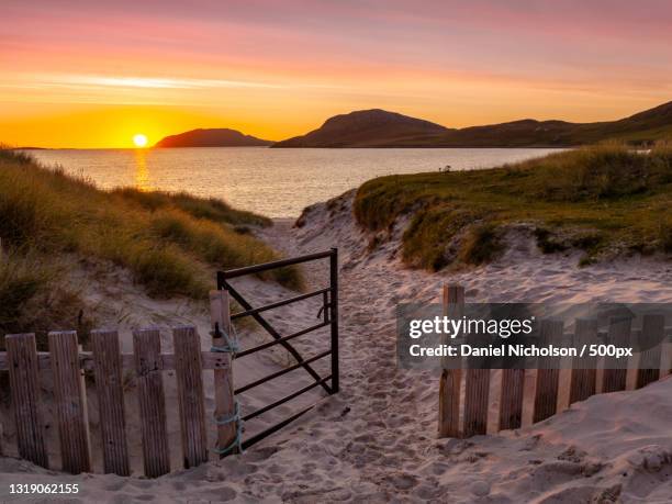 scenic view of sea against sky during sunset,vatersay,united kingdom,uk - beach fence stock-fotos und bilder