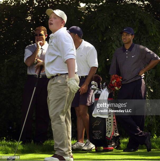 Tiger Woods watches as 15-year-old Andrew Giuliani tees off during a pro-am tournament at the Westchester Country Club in Harrison, New York on June...