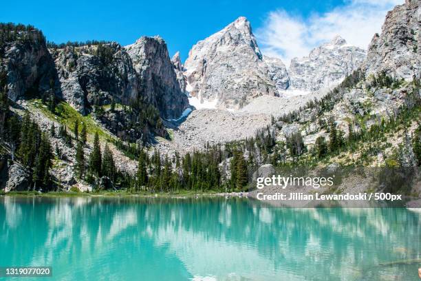 scenic view of lake by snowcapped mountains against sky,grand teton,wyoming,united states,usa - grand teton stock-fotos und bilder