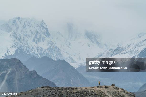 frau steht auf felsen auf dem hintergrund des schneebedeckten bublimotin-gipfels in nordpakistan - gilgit stock-fotos und bilder