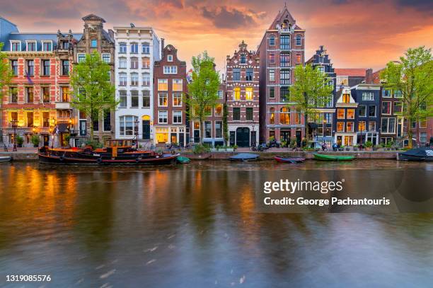 dramatic clouds over a canal in amsterdam, the netherlands - amsterdam photos et images de collection
