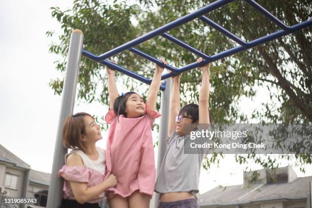 asian chinese mother and children playing on monkey bars public park. - monkey bars stock pictures, royalty-free photos & images