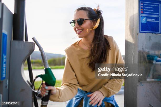 beautiful woman refueling the gas tank at fuel pump - filling stock pictures, royalty-free photos & images