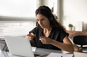 Concentrated female in headset sit by pc support client remotely