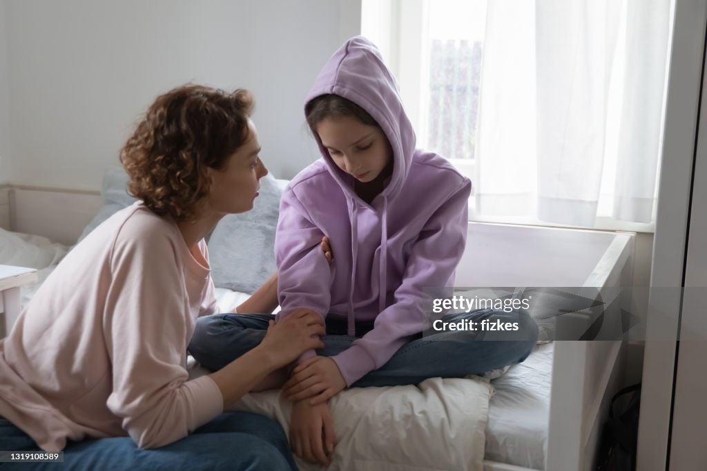 Jovem mamãe carinhosa apoiando a filha adolescente estressada.