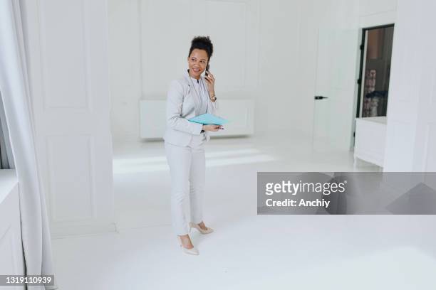 real estate agent waiting for clients and talking on the phone in an empty space - commercial real estate agent stock pictures, royalty-free photos & images