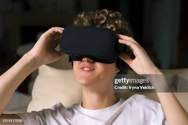 young man or teenager in a white t-shirt wearing virtual reality goggles during the vr experience. - top prospects game stockfoto's en -beelden