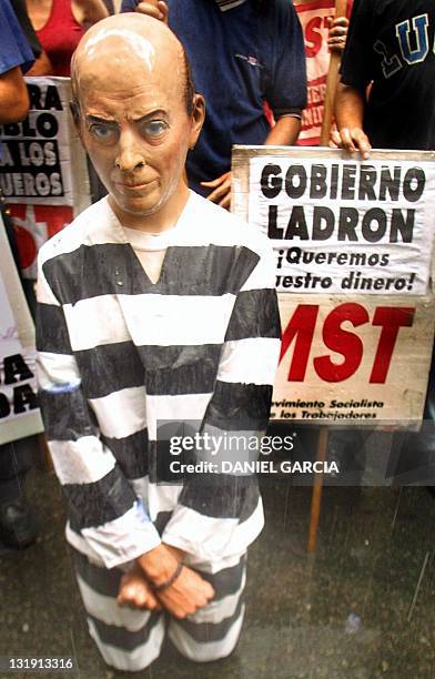 Man costumed in a mask of Argentina Economic Minister Domingo Cavallo sits tied-up and kneeling before stikers in Buenos Aires, Argentina 13 December...