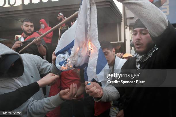 Pro Palestinian protesters burn the Israeli flag as they face off with a group of Israel supporters and police in a violent clash in Times Square on...