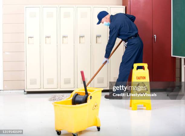 senior adult janitor mops floor in school locker room. - school caretaker stock pictures, royalty-free photos & images