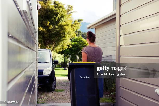 frau putting recycling bin out - mülleimer auf rollen stock-fotos und bilder