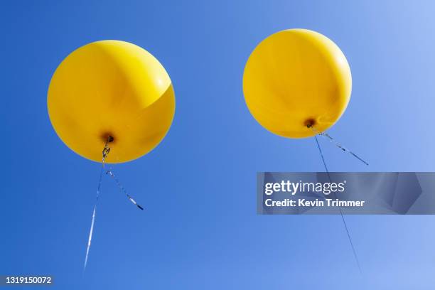 large yellow balloons in sky - globo de helio fotografías e imágenes de stock