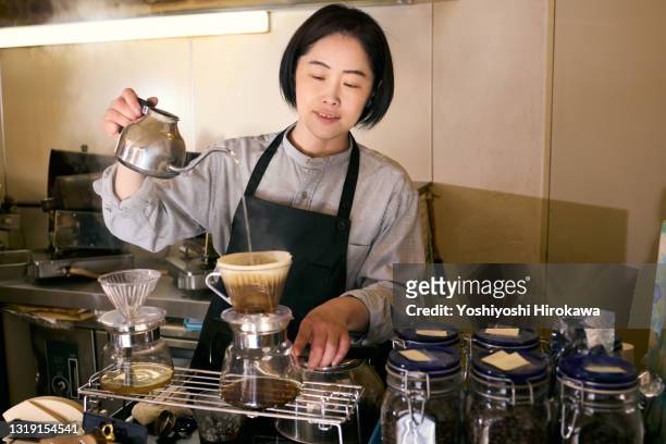 woman in her 40s brewing coffee for a customer at coffee shop - filterkaffee stock-fotos und bilder