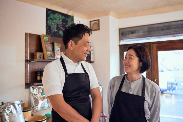 genuine portrait of sincere couple selling their roasted world specialty coffee beans to customer's order in tokyo - professional coffee roaster stock pictures, royalty-free photos & images