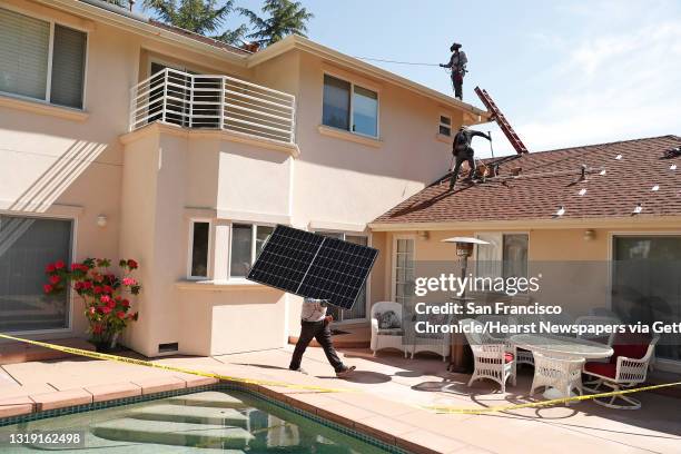 Sunrun employee Gonzalo Najera carries a solar panel before installation at a home in Alamo, Calif., on Monday, May 17, 2021.