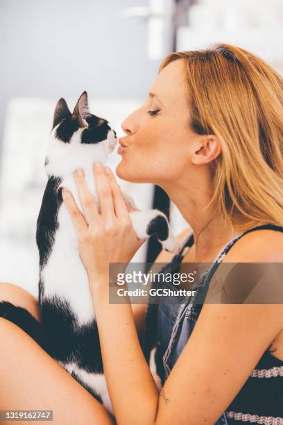 ragazza caucasica giocosa che gioca con il suo gattino - black and white cat foto e immagini stock