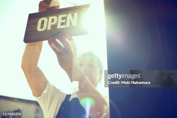 the store owner hangs an opensign on the door. - reabertura - fotografias e filmes do acervo