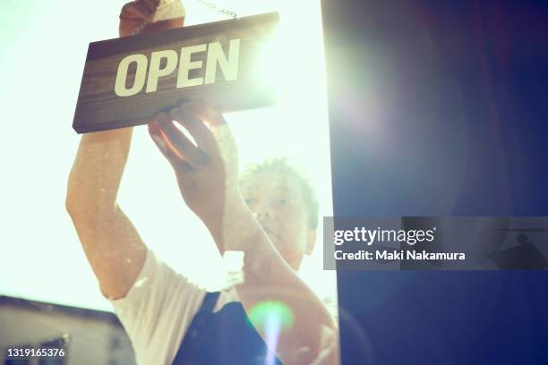 the store owner hangs an opensign on the door. - butiksinvigning bildbanksfoton och bilder