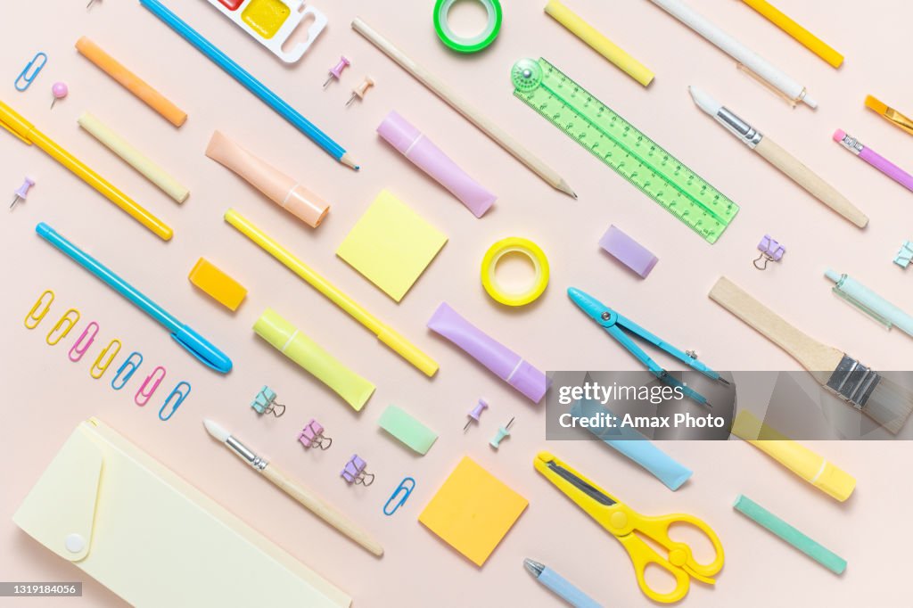 Top view of colorful frame banner with school supplies. Pastel pink background with copy space. Back to school concept.