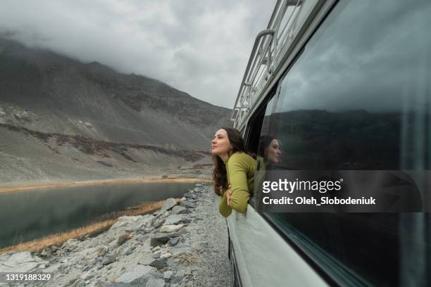woman looking at mountains of northern pakistan from window in the van - beauty in nature stock pictures, royalty-free photos & images