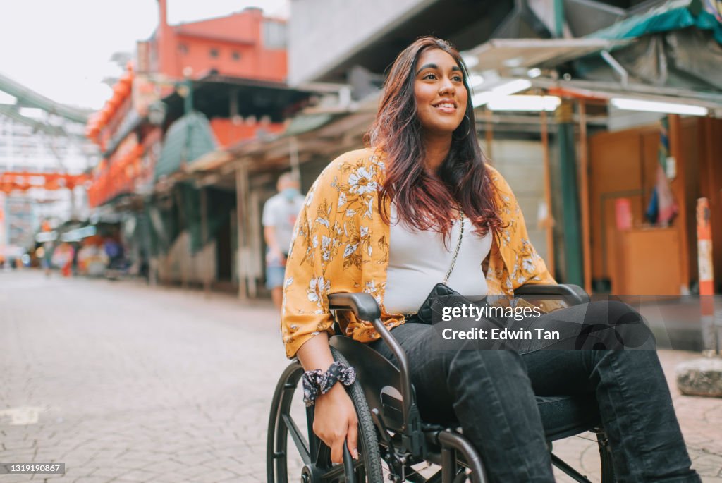 Asiatische indische schöne Frau mit Behinderung mit Rollstuhl erkunden Innenstadt in kuala lumpur